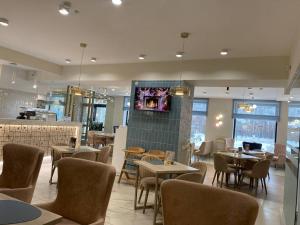 a restaurant with tables and chairs and a tv on the wall at River Stone in Pavlodar