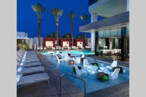 a pool with white lounge chairs and palm trees at Palms Place No Resort fees with Balcony in Las Vegas