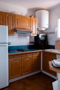 a kitchen with wooden cabinets and a white refrigerator at Charming apartment in Porto-Vecchio in Porto-Vecchio