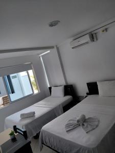 two beds in a small room with a window at Hotel Los Potrillos in Aguazul