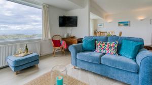 a blue couch in a living room with a window at Borth Mawr in Rhosneigr
