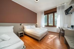 a hotel room with two beds and a desk at Ventus Park Hotel in Nago-Torbole