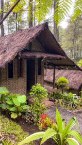 a small house with a grass roof in a garden at ALAMSUKA Cikole in Tangkubanperahu