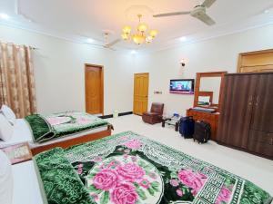 a hotel room with two beds and a television at Rose Palace Guest House in Karachi