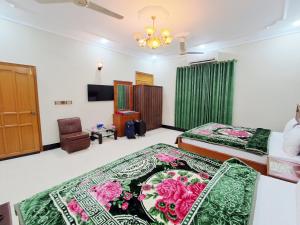 a bedroom with two beds and a television in it at Rose Palace Guest House in Karachi +71 photos