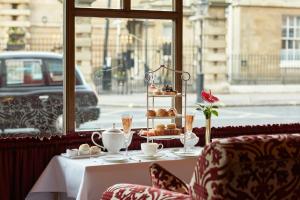 a table with a plate of pastries and a table with a window at Rubens At The Palace in London