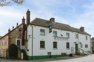 a white building with a black horse sign on it at The Black Horse in Amberley