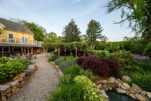 a garden in front of a house with a creek at Stonecroft Inn in Ledyard Center