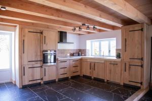 a large kitchen with wooden cabinets and a window at Domaine des Chênes in Saint-Pierre-les-Étieux