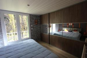 a bedroom with a bed and a large window at Maison au bord de l'eau avec Jacuzzi in Millau