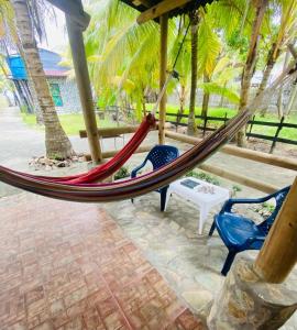 a hammock in a resort with two chairs and palm trees at Gaia - Casa de Playa in San Bernardo del Viento
