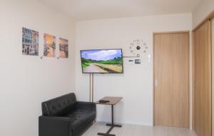 Ein Zimmer mit einem schwarzen Sessel und einem Fernseher an der Wand in der Unterkunft Trattoria&BarTroppo in Hayaki
