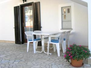Biały stół i krzesła na patio z rośliną w obiekcie Apartmani Dolencic w Krku