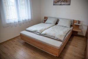 a bed in a room with a wooden floor at La Palma Gúta in Kolárovo
