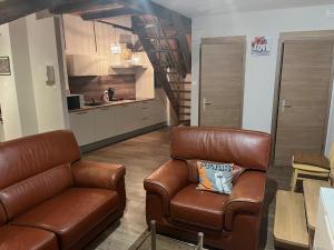 a living room with a leather couch and a kitchen at Duplex rénové avec terrasse privative à 10 mm de Colmar et Eguisheim, à 2 mm du grand axe autoroutier Strasbourg Mulhouse in Sainte-Croix-en-Plaine