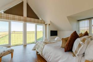 a white bedroom with a large bed and large windows at Taigh Gleusta in Angus