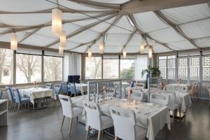 ein Esszimmer mit Tischen, Stühlen und Fenstern in der Unterkunft Bastion Heritage Hotel in Zadar