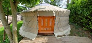 a yurt with an orange door in a yard at Chez Jo et Mel - Gite et Yourtes in Bannost