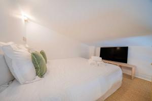a bedroom with a white bed and a television at Studio in a residence with pool - Saint-Tropez in Saint-Tropez
