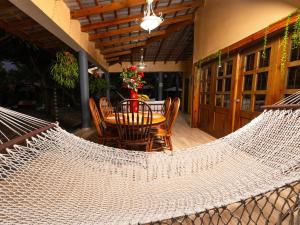 a hammock on a patio with a table and chairs at Villa Rosalía con Piscina Climatizada in Jarabacoa