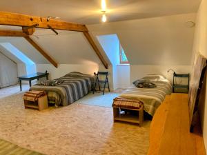 a attic bedroom with two beds and a table at LES PIPISTRELLES 19 - GITE et Chambre d'hôtes in Meymac