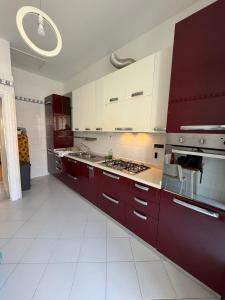 a large kitchen with red cabinets and white tile floors at Naturalis Historia Meta in Meta