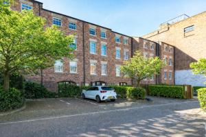 a white car parked in front of a large brick building at Ward St Residence - Parking - Lpool City Centre in Liverpool