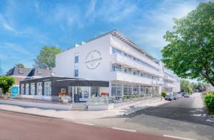 a white building with a clock on it on a street at Hotel Yachtclub in Timmendorfer Strand