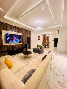 a living room with a couch and a tv on a wall at 3BED flat close to the airport lagos in Lagos