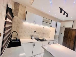 a white kitchen with white cabinets and a sink at 3BED flat close to the airport lagos in Lagos