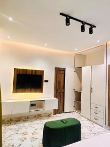 a living room with a television and a green ottoman at 3BED flat close to the airport lagos in Lagos +32 photos