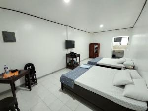 a bedroom with two beds and a desk and a television at Tiza Manor Inn in Roxas City