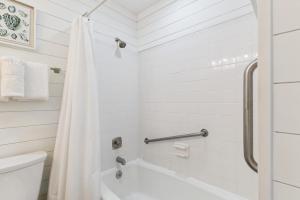 a white bathroom with a tub and a toilet at Beachcomber, Unit 302 in Demere Park +17 photos