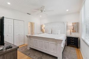 a white bedroom with a bed and a ceiling fan at Beachcomber, Unit 302 in Demere Park