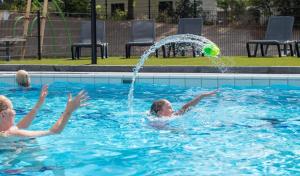 two girls playing with a ball in a swimming pool at Chalet Vakantie Wageningen Veluwe in Wageningen