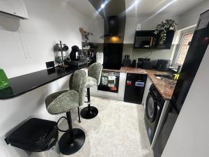 a kitchen with two bar stools and a counter at Stylish 1-Bed Apartment in Chester with Parking & Full Kitchen in Chester