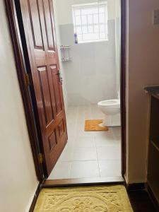 a bathroom with a toilet and a wooden door at Eunas homestay in Eldoret +5 photos