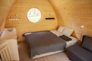 a bedroom in a log cabin with a bed and a window at Meža namiņi Sprīdīši in Tērvete