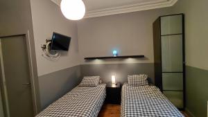two beds in a room with a tv on the wall at B&B De Gastfabriek in Tielt