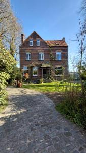 a large brick house with a brick driveway at B&B De Gastfabriek in Tielt