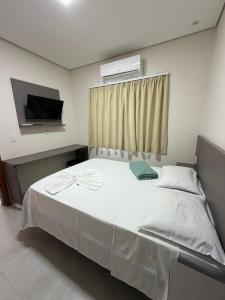 a bedroom with a large white bed with a window at Hotel Colorado in Vilhena