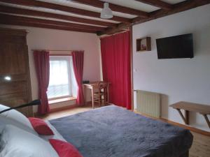 a bedroom with a bed with red curtains and a television at L'amandier in Thouars