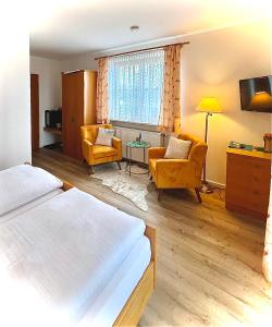 a hotel room with a bed and chairs and a television at Gästehaus Bauer am Golfplatz in Prien am Chiemsee