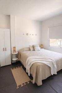 a white bedroom with a large bed and a window at Casa Tetis in La Floresta