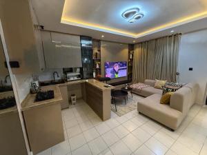 a kitchen and a living room with a couch and a tv at Caramel Cove Lekki in Mama