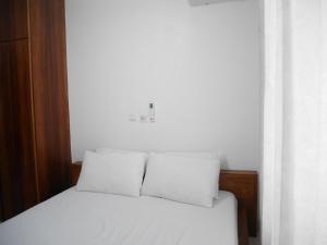 a white bed with two pillows on top of it at LA MAISON SEONE f4 FAMILLE in Abidjan