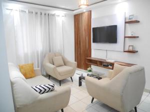 a living room with two chairs and a flat screen tv at LA MAISON SEONE f4 FAMILLE in Abidjan