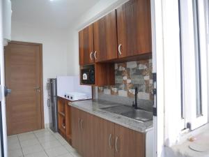 a kitchen with wooden cabinets and a sink and a refrigerator at LA MAISON SEONE f4 FAMILLE in Abidjan