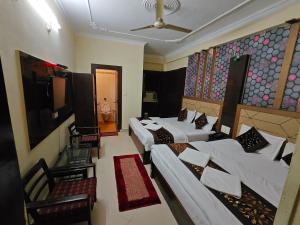 a hotel room with three beds and a tv at Hotel jewel in Haridwār +54 photos