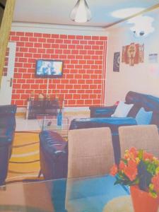 a living room with leather furniture and a brick wall at Appartement bonita in Dakar